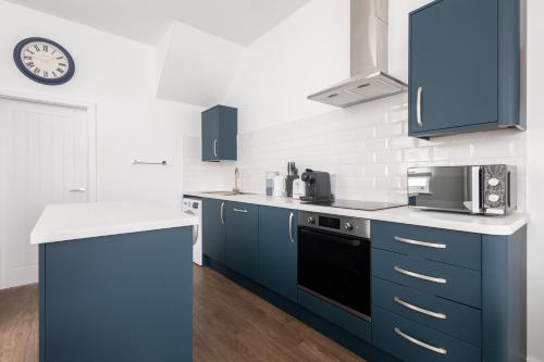 a kitchen with blue cabinets and a clock on the wall at Host & Stay - Sanderling Chase in Scarborough