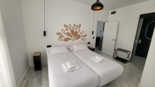 a bedroom with a white bed with two white towels at RentalSevilla Real de la Carretería in Seville