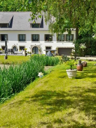 a large white house with a yard with plants at Gite au Reflet d'Auvers in Auvers-sur-Oise
