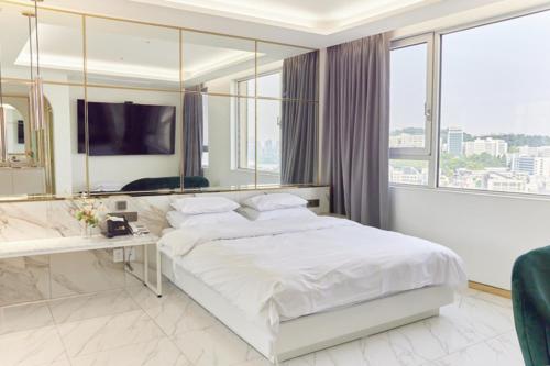a bedroom with a white bed and a large window at Hotel The Designers Hongdae in Seoul
