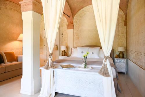 a bedroom with a white bed with curtains at Elizabeth Country House, a Member of Design Hotels in Minerbio