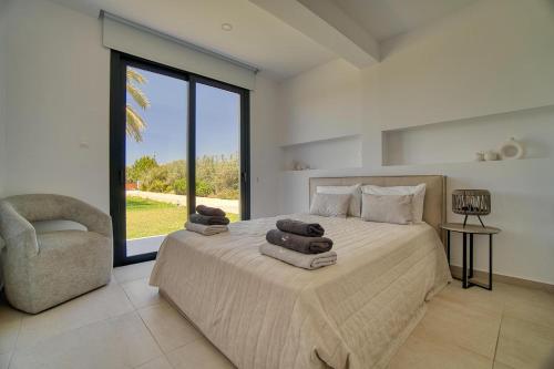 a bedroom with a bed and a chair and a window at Luxury Oasis Villa in Peyia