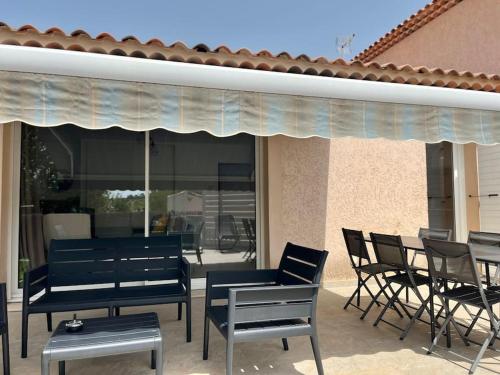 un groupe de chaises et de tables sur une terrasse dans l'établissement Maison proche des plages, à Ceyreste