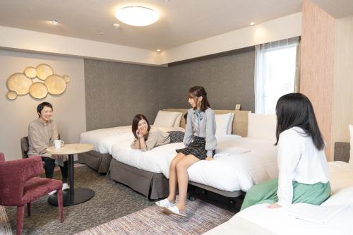 a group of people sitting on beds in a hotel room at Richmond Hotel Akita Ekimae in Akita