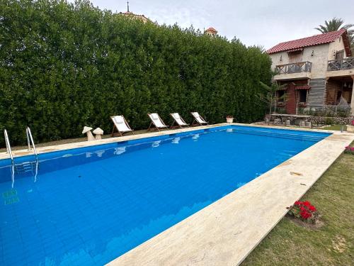 a swimming pool with lounge chairs next to a house at Jasmin Holiday House in Alexandria