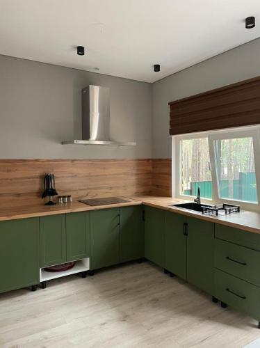 Una cocina con gabinetes verdes y una ventana. en Ormanhouse, en Shchūchīnsk