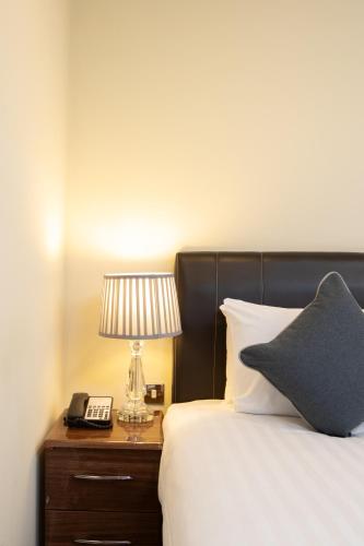 a bedroom with a bed with a lamp and a phone at Grand Plaza Serviced Apartments in London