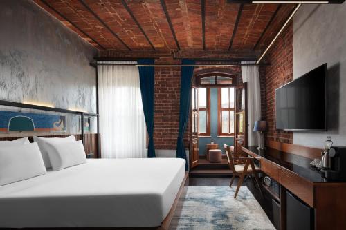 a bedroom with a large white bed and a tv at DeCamondo Galata, a Tribute Portfolio Hotel in Istanbul