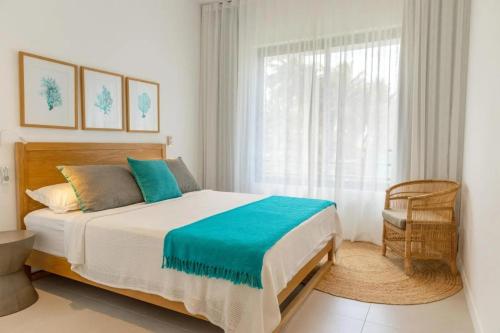 a bedroom with a bed and a window and a chair at Blue Nest Luxury Penthouse in Blue Bay