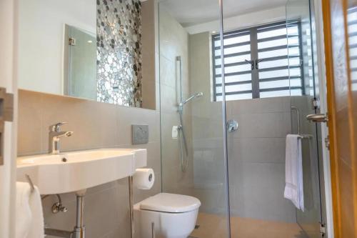 a bathroom with a sink and a toilet and a shower at Blue Nest Luxury Penthouse in Blue Bay