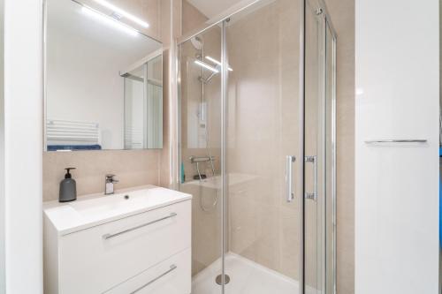 La salle de bains est pourvue d'une douche et d'un lavabo blanc. dans l'établissement Résidence Gabrielle - Proche de Paris, à Bondy