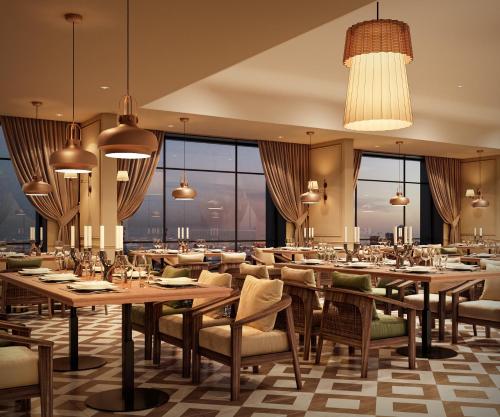 a restaurant with tables and chairs and large windows at Treat Hotel Nashik City Center in Nashik