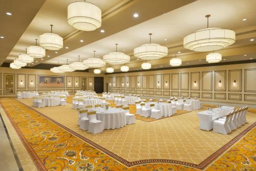 a large banquet hall with white tables and chandeliers at Treat Hotel Nashik City Center in Nashik