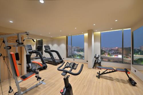 a gym with treadmills and ellipticals in a room with windows at Treat Hotel Nashik City Center in Nashik