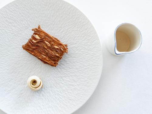 a white plate with a piece of food and a cup of coffee at La Villa Calvi in Calvi