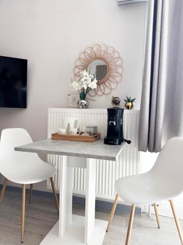 - une table à manger avec des chaises blanches et un miroir dans l'établissement Le Bali, studio évasion proche aéroport, à Saint-Louis