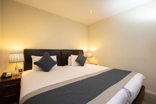 a bedroom with a large bed with two pillows at Grand Plaza Serviced Apartments in London