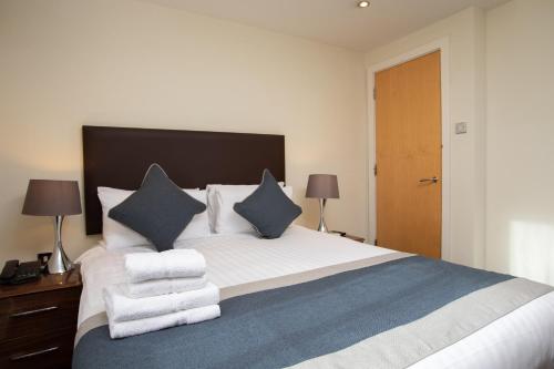 a bedroom with a large white bed with blue pillows at Grand Plaza Serviced Apartments in London