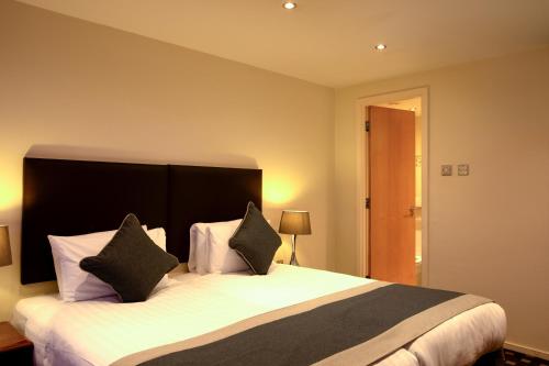 a bedroom with a large bed with two pillows at Grand Plaza Serviced Apartments in London