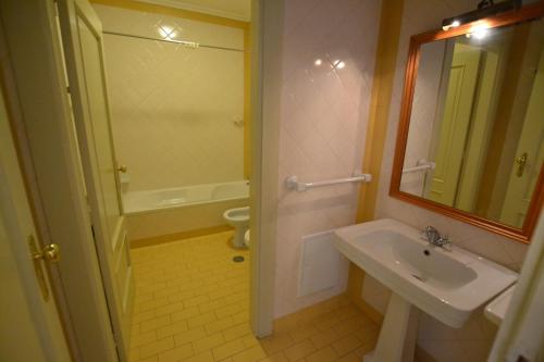 W łazience znajduje się umywalka, toaleta i lustro. w obiekcie Casa do Condado de Beirós w mieście São Pedro do Sul