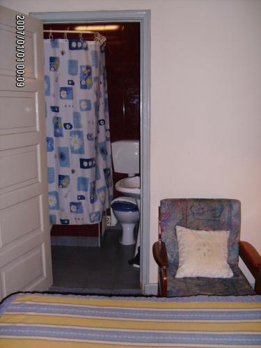 a bathroom with a toilet and a chair at Olhos Pretos in Caldas da Rainha