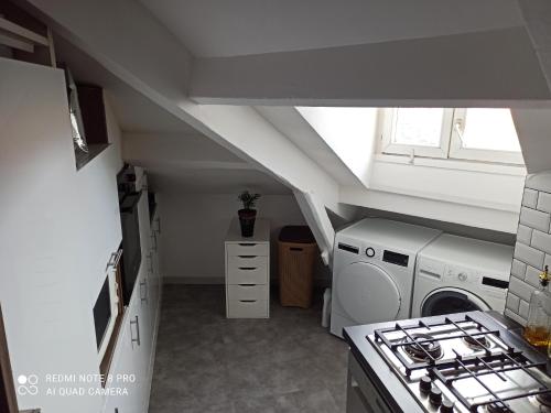 une cuisine mansardée avec une laveuse et une sécheuse à l'intérieur dans l'établissement F3 A 400 m du Stade de France JO, à Saint-Denis