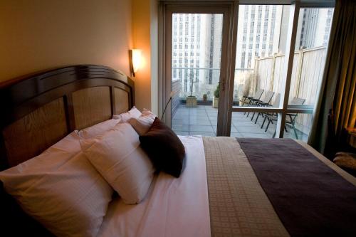 a bedroom with a bed with white pillows and a balcony at Hotel Mulberry in New York