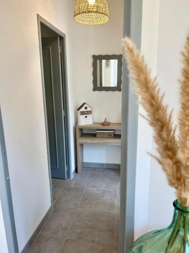 - un couloir avec un miroir et un vase au sol dans l'établissement Le chaurien - central et climatisé - local vélo, à Castelnaudary
