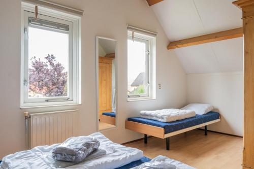 two beds in a room with two windows at Vakantiewoning in villapark de oesterbaai 113 in Wemeldinge