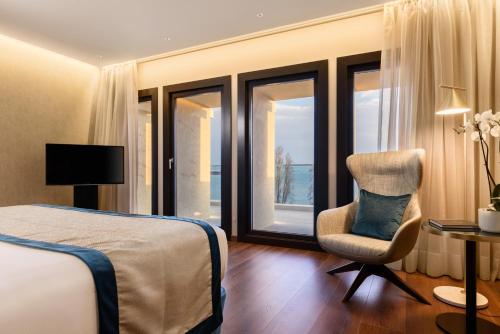 a bedroom with a bed and a chair and windows at Áurea Museum by Eurostars Hotel Company in Lisbon