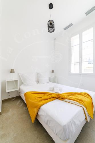 une chambre blanche avec un grand lit avec une couverture jaune dans l'établissement Élégance Côtière - Vue imprenable, Plage à 5 min, à Toulon