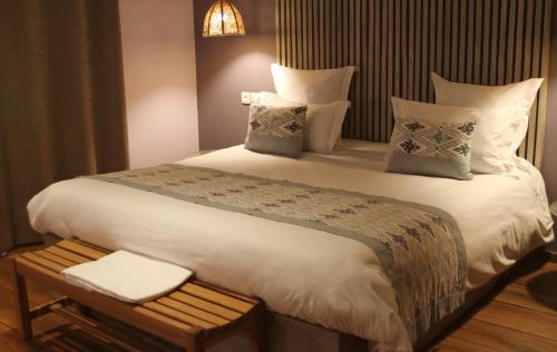 a bedroom with a large bed with white sheets and pillows at Nosy Manga - Hotel Ivato Airport in Antananarivo