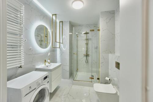 a white bathroom with a shower and a washing machine at Balticus Apartament Promenada Gwiazd 14 in Międzyzdroje