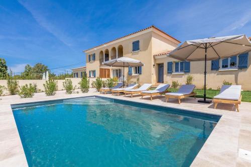 - une piscine en face d'une maison avec des parasols dans l'établissement Résidence Casaviva, à Calvi