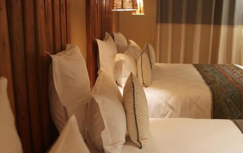 a bedroom with two beds with white pillows at Nosy Manga - Hotel Ivato Airport in Antananarivo