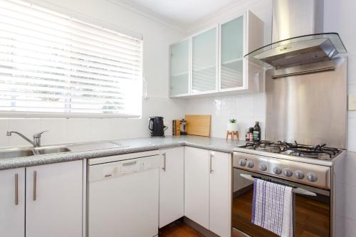 a kitchen with white cabinets and a stove top oven at Hillarys Hideaway in Perth