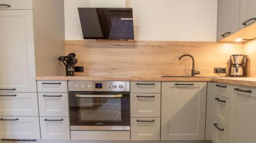 a kitchen with white cabinets and a stainless steel oven at Ferienwohnung Zweite Heimat in Mieders