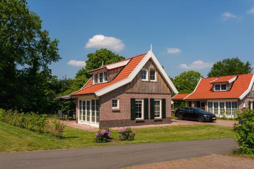 a house with an orange roof and a car in the driveway at The Pimpelmees in Hoge-Hexel