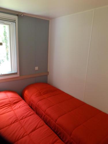 - 2 lits rouges dans une chambre avec fenêtre dans l'établissement SUN Camping, à Sampzon