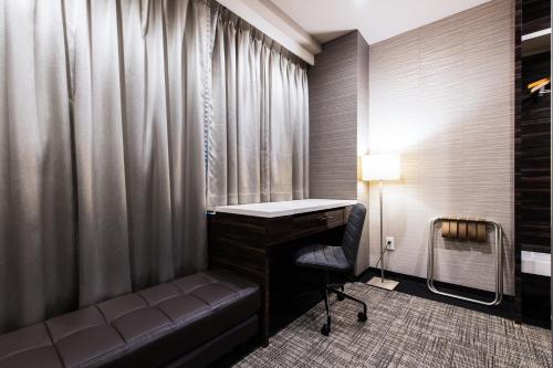 a room with a desk and a chair next to a window at Urvest Hotel Kamata in Tokyo