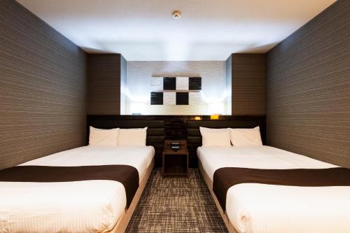 two beds in a hotel room with a window at Urvest Hotel Kamata in Tokyo