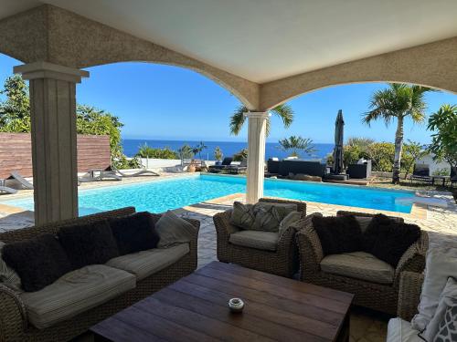 a swimming pool with two couches and a table at VILLA POINTE DES CHATEAUX VUE IMPRENABLE in Saint-Leu