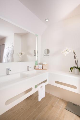 a white bathroom with a sink and a mirror at Akoya Hotel & Spa in Saint-Gilles les Bains