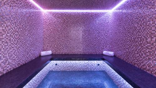 a pink tiled bathroom with a tub with purple lights at Akoya Hotel & Spa in Saint-Gilles les Bains