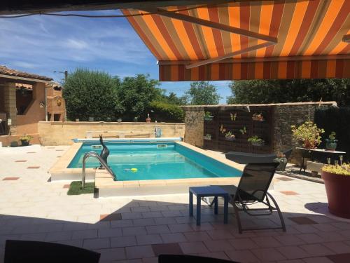 - une piscine avec une chaise et un parasol dans l'établissement Charmant studio avec piscine partagée à Sernhac - 30 m², à Sernhac