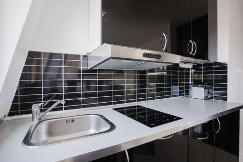 une cuisine avec un évier et un mur carrelé noir dans l'établissement Joli studio Deauville, à Deauville