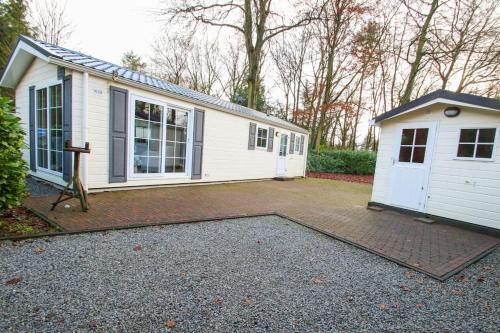 a small white house with a garage at Luxe vrijstaande chalet in Epe