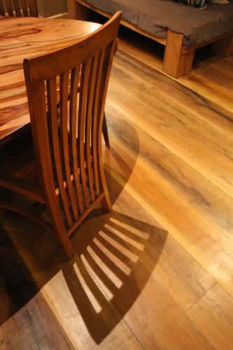 a wooden chair is casting a shadow on a wooden floor at Nosy Manga - Hotel Ivato Airport in Antananarivo