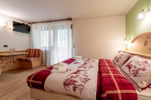 a bedroom with a large bed and a window at Hotel Villetta Maria Cottage in Canazei