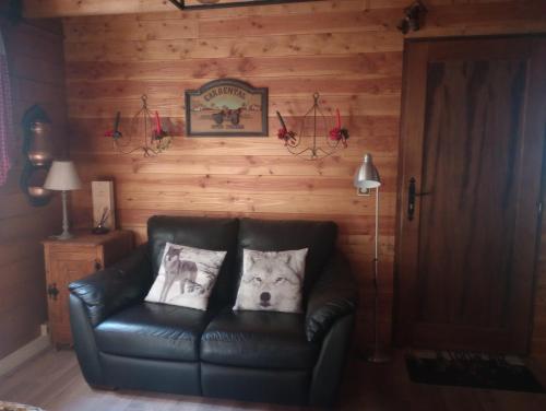ein Ledersofa mit zwei Kissen darauf in einem Zimmer in der Unterkunft L'ARGOUSIER Chalet 6 à 8 personnes Enchastrayes Barcelonnette in Enchastrayes